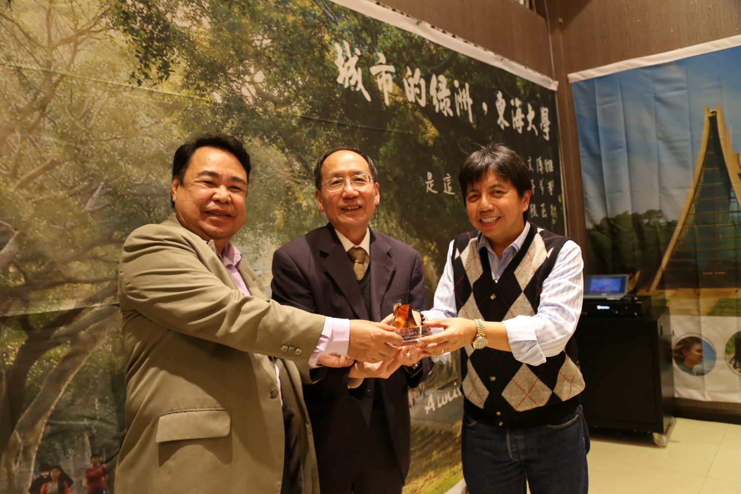 -	President Mao-Jiun Wang presented a glass Luce Chapel to Dr. Alex B. Brillantes (right) of CHED and Executive Director Dr. Herbert Glenn P. Reyes (left) of the Philippines Public University Alliance.